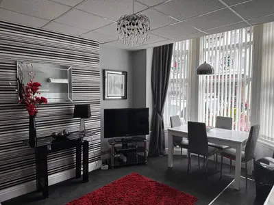 a dining room with a table and a television at Berkswell Holiday Apartments in Blackpool