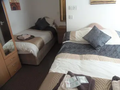 a hotel room with two beds and a mirror at Oban House in Blackpool