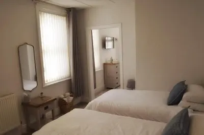 a bedroom with two beds and a mirror and a window at Avenue Guest House in Blackpool