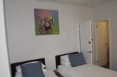 a bedroom with two beds and a painting of a cow at Avenue Guest House in Blackpool