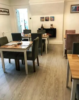 a dining room with tables and chairs and a fireplace at Avenue Guest House in Blackpool