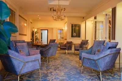 a waiting room with blue chairs and a chandelier at Clifton Park Hotel - Adults Only in Lytham St Annes