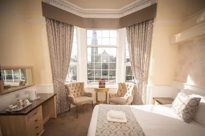 a bedroom with a bed and two chairs and a window at Clifton Park Hotel - Adults Only in Lytham St Annes
