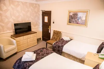 a hotel room with two beds and a television at Clifton Park Hotel - Adults Only in Lytham St Annes
