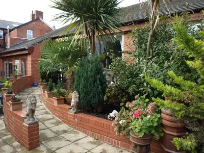 a garden with plants and trees and a brick fence at Clifton Park Hotel - Adults Only in Lytham St Annes