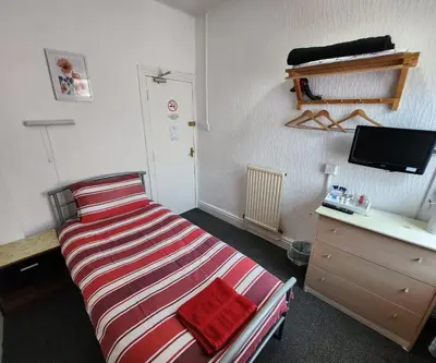 a bedroom with a bed and a desk with a television at The Moorfield in Blackpool