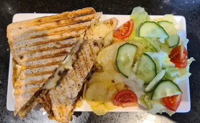 a plate of food with a sandwich and a salad at The Pavilion Guest House in Millom