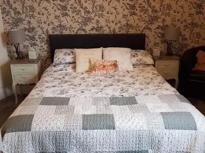 a bed with a quilt and pillows on top of it at The Pavilion Guest House in Millom