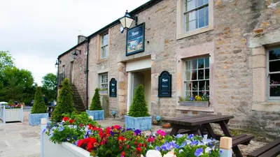 a stone building with flowers in front of it at The Fleece Inn in Shireshead