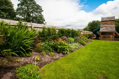 a garden with a fence and many plants at The Fleece Inn in Shireshead