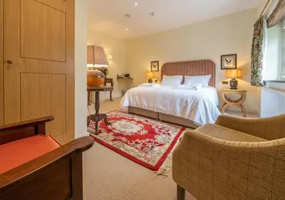 a bedroom with a white bed and a red rug at The Fleece Inn in Shireshead