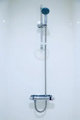 a shower with a light on a white wall at The Liverpool Pod Travel Hostel in Liverpool