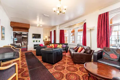 a living room with leather furniture and red curtains at The Headlands in Blackpool