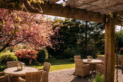 a patio with tables and chairs under a wooden pergola at The Shireburn Arms in Clitheroe
