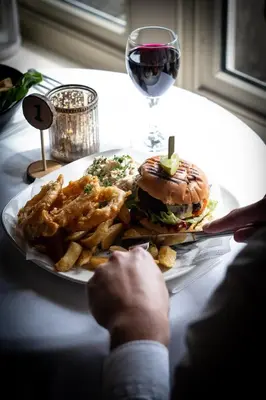 a plate with a hamburger and french fries and a glass of wine at The Shireburn Arms in Clitheroe
