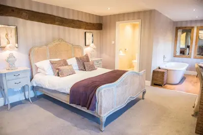 a bedroom with a bed and a bathroom with a tub at The Shireburn Arms in Clitheroe