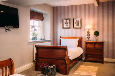 a bedroom with a bed with a dresser and a television at The Shireburn Arms in Clitheroe