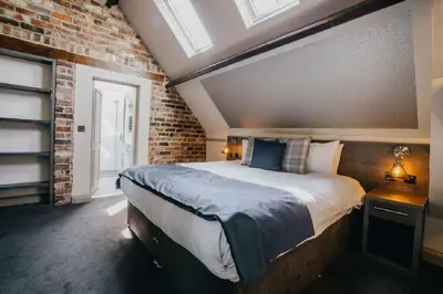 a bedroom with a bed and a brick wall at The Duke of Edinburgh Hotel & Bar in Barrow in Furness