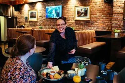 a woman sitting at a table with a plate of food at The Duke of Edinburgh Hotel & Bar in Barrow in Furness