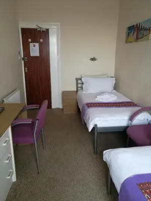 a hotel room with two beds and a table and chairs at Westleigh B&B in Morecambe