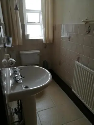 a bathroom with a sink and a toilet and a window at Westleigh B&B in Morecambe
