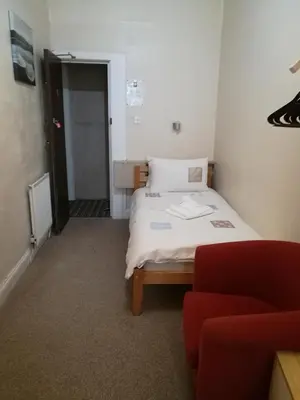 a small room with a bed and a red couch at Westleigh B&B in Morecambe