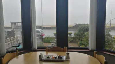 a table and chairs in a room with windows at Westleigh B&B in Morecambe