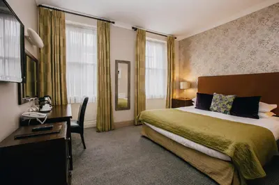 a hotel room with a bed and a desk and window at The Sun Hotel & Bar in Lancaster