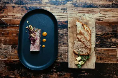 a black plate with a piece of bread and a sandwich at The Sun Hotel & Bar in Lancaster