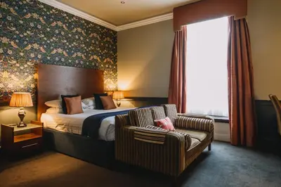 a bedroom with a bed and a chair and a window at The Sun Hotel & Bar in Lancaster