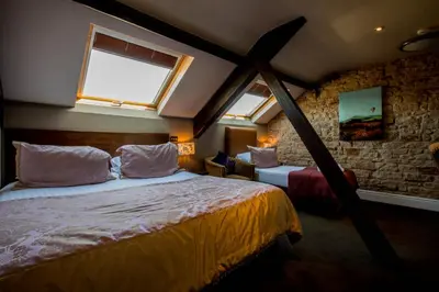 a bedroom with two beds and two windows at The Sun Hotel & Bar in Lancaster