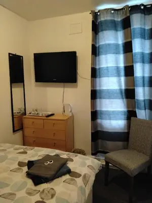 a bedroom with a bed and a tv and a chair at Fern Villa Hotel - Albert Road in Blackpool