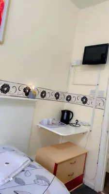 a room with a desk and a shelf with a tv at Fern Villa Hotel - Albert Road in Blackpool
