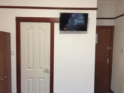 a room with a door with a tv on the wall at Fortuna House Hotel in Blackpool
