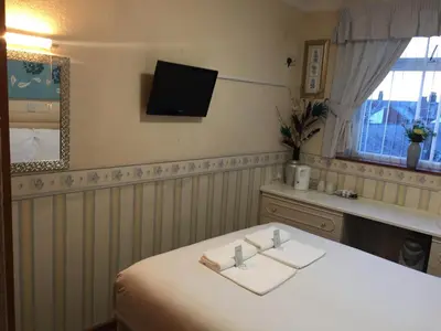 a room with a white table with a tv on the wall at Fortuna House Hotel in Blackpool