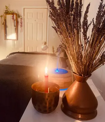 a candle and a vase on a table with a bed at Log home village in Ulverston