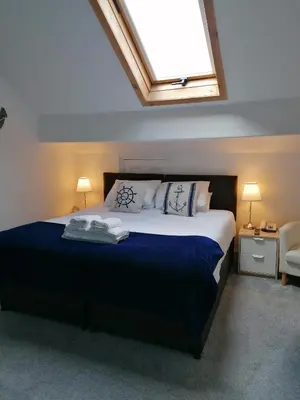 a bedroom with a large bed with a blue blanket at Edendale House in Southport