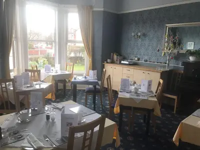 a dining room with tables and chairs and windows at Edendale House in Southport