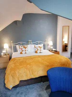 a bedroom with a large bed and a blue chair at Edendale House in Southport