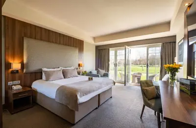 a hotel room with a large bed and a desk at Formby Hall Golf Resort & Spa in Southport