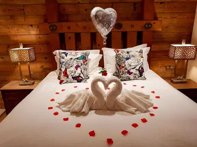 two white swans are sitting on a bed with hearts at Lymestone Boutique Accommodation in Grange Over Sands
