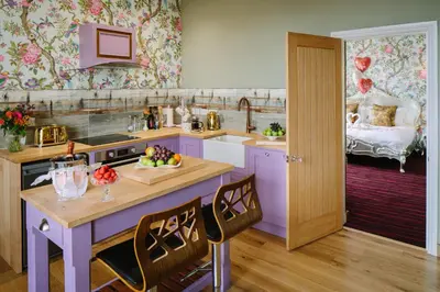 a kitchen with a table with a bowl of fruit on it at Lymestone Boutique Accommodation in Grange Over Sands