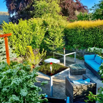 a garden with a blue couch and a table at Lymestone Boutique Accommodation in Grange Over Sands