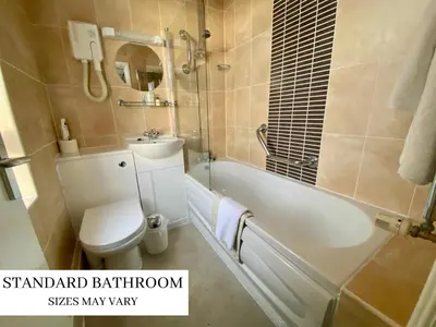 a bathroom with a toilet and a tub and a sink at Doric Hotel in Blackpool