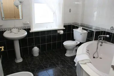 a bathroom with a sink and a toilet and a tub at Doric Hotel in Blackpool