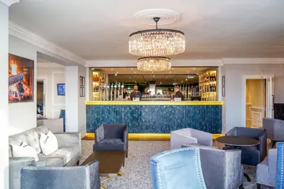 a lobby with a bar with blue chairs at Doric Hotel in Blackpool