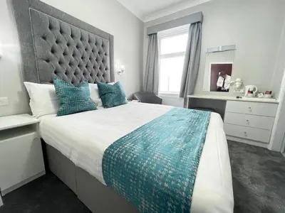 a bedroom with a large bed with blue pillows at Doric Hotel in Blackpool