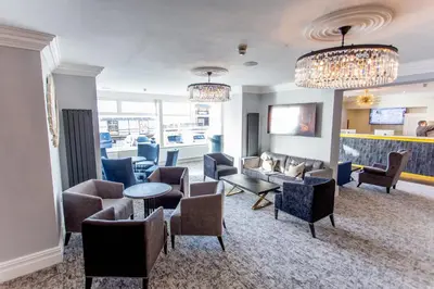 a waiting room with couches and tables and chairs at Doric Hotel in Blackpool
