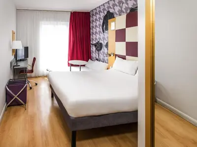 a hotel room with a large white bed and a window at ibis Styles Haydock in Haydock