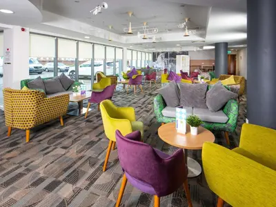 a waiting room with colorful chairs and tables at ibis Styles Haydock in Haydock